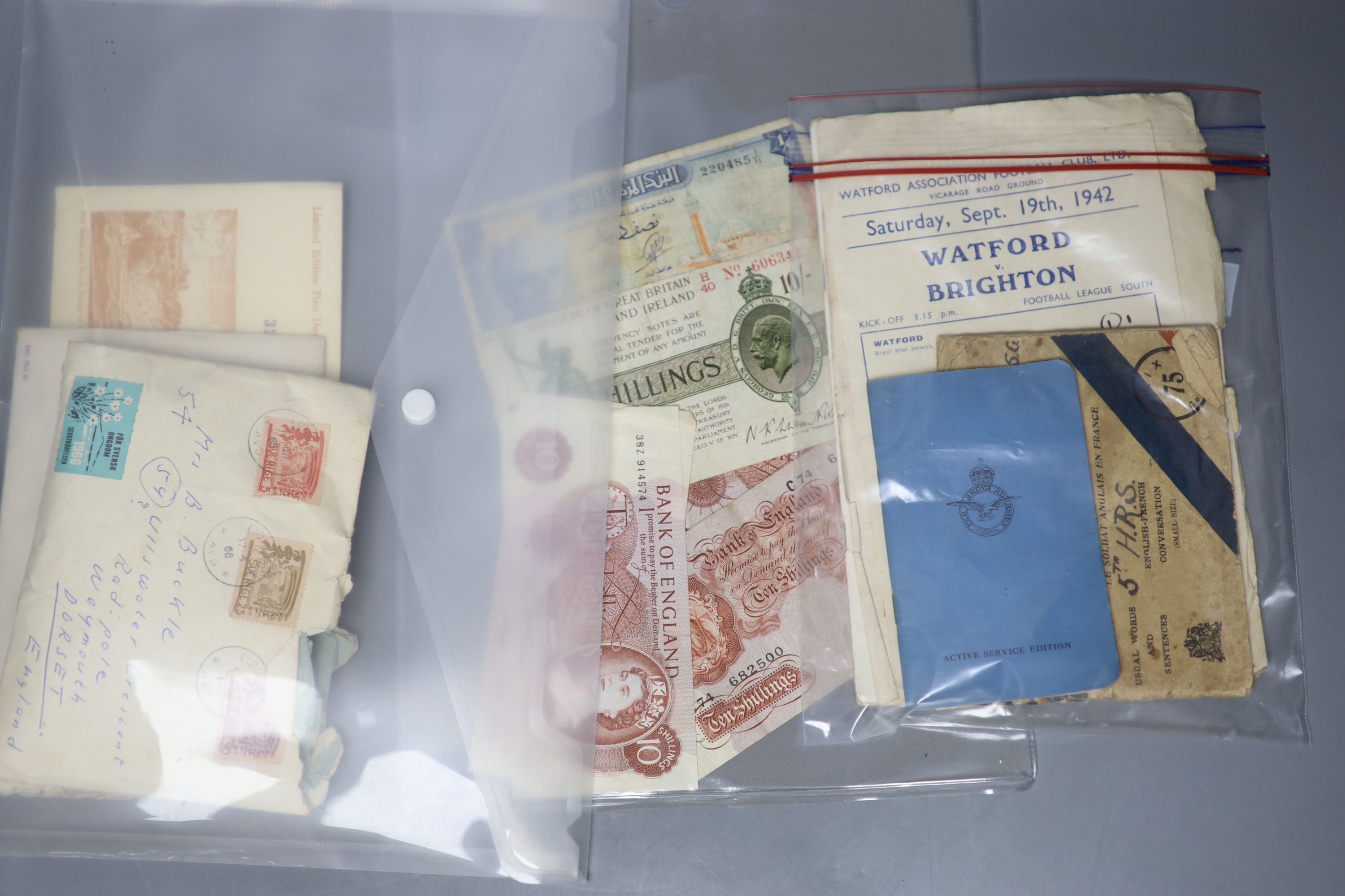 A collection of stamps, coins, banknotes, football programmes from 1942, playing cards and a book.